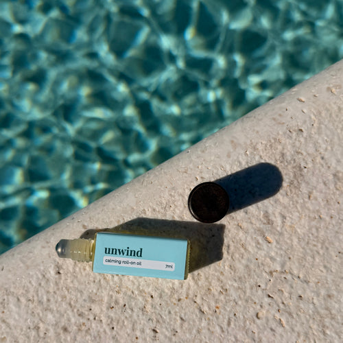 Skincare product labeled 'unwind' by a pool